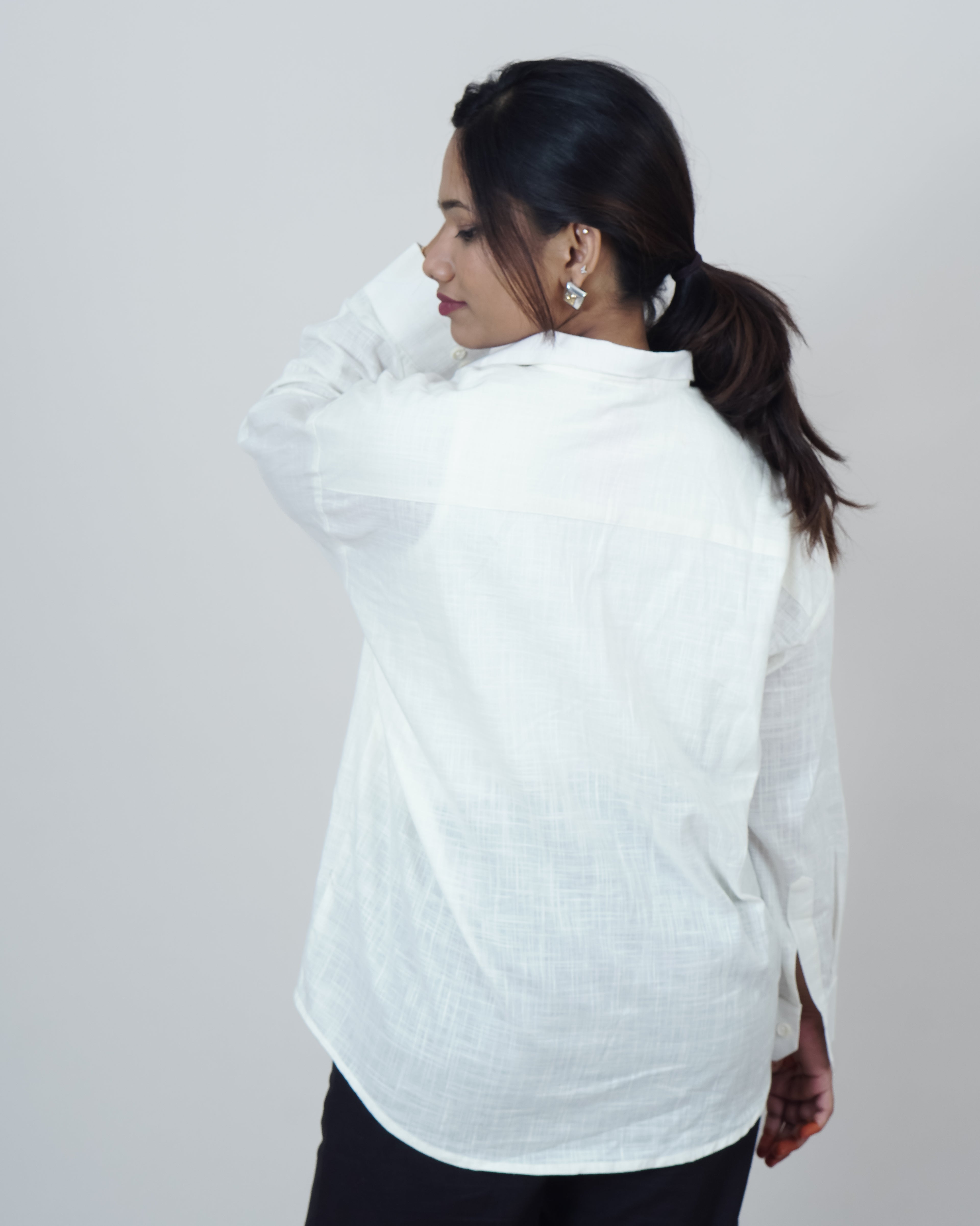 Woman wearing a white textured shirt against a plain background