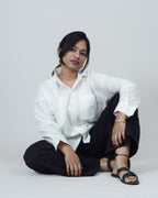 Person wearing a white shirt and black pants sitting on a white background