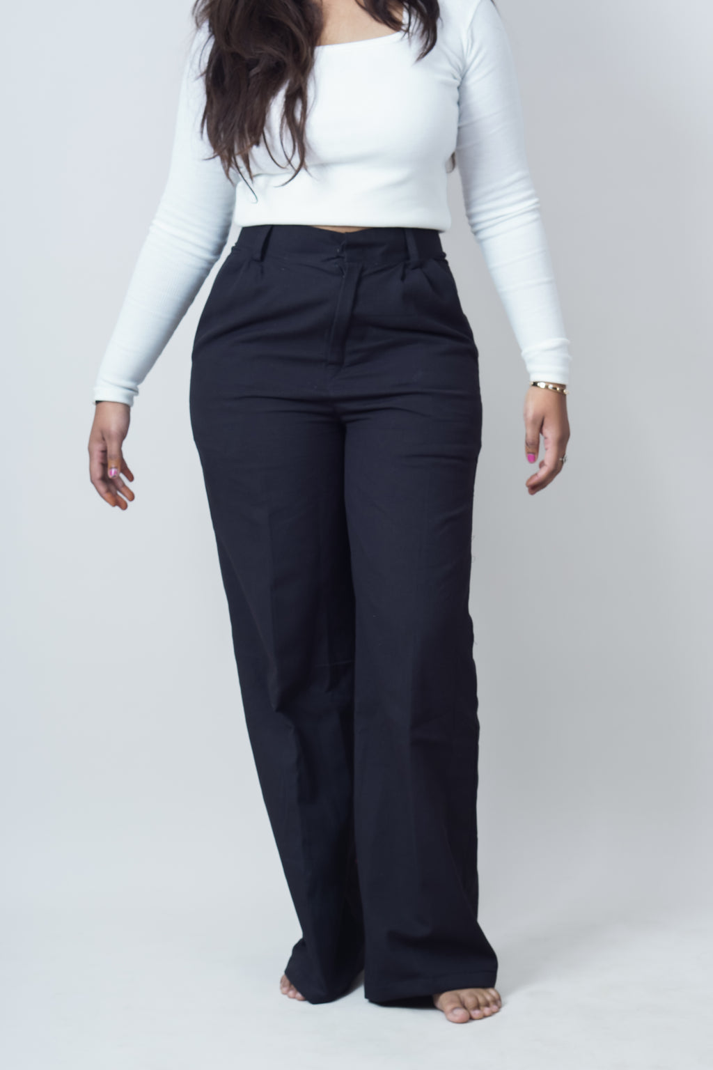 Person wearing a white long-sleeve top and black wide-leg pants on a white background